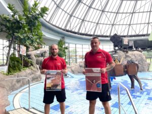 Weltkindertag im Aquapark Oberhausen: Männer mit Plakat vor Schwimmbecken