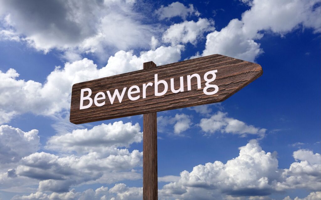 Bewerbung: Schild mit Schriftzug vor Wolkenhimmel