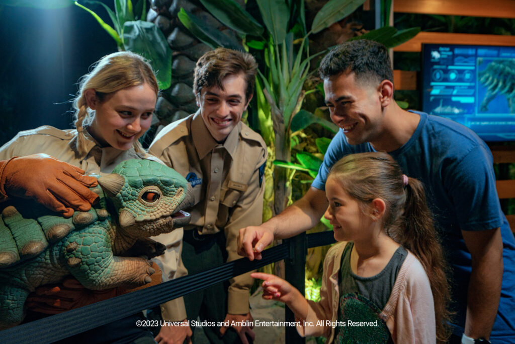 Jurassic World: The Exhibition: Vier Personen bewundern einen kleinen Dino