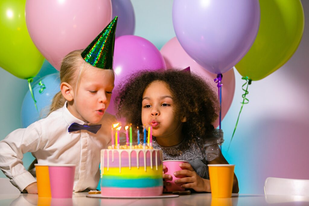 Kindergeburtstags-Tipps: Zwei Kinder pusten Kerzen auf Torte aus.