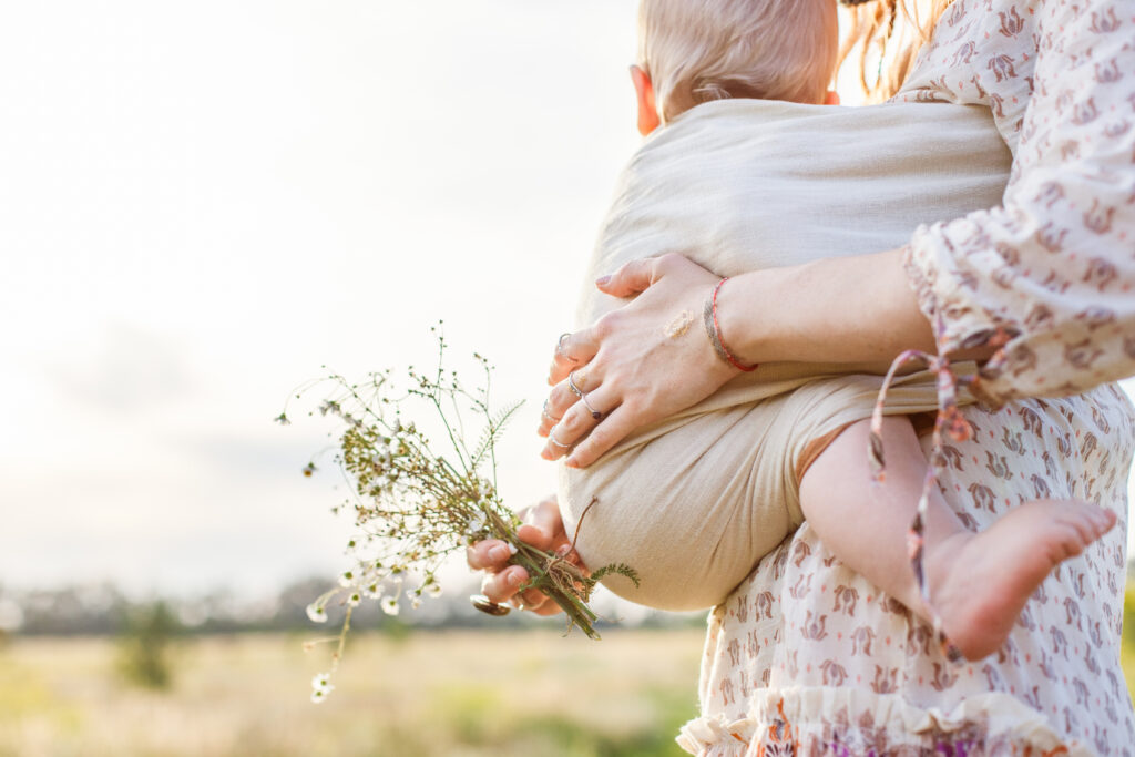 Tragehilfe: Frau mit Baby vor sich im Tragetuch