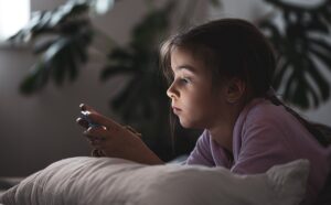 Cybergrooming: Liegendes Mädchen guckt auf ihr Smartphone