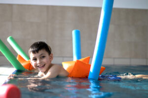 Vorbereitung auf den Schwimmkurs: Junge mit Schwimmnudel im Becken