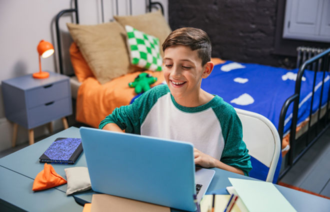 Junge lernt in seinem Zimmer am Laptop